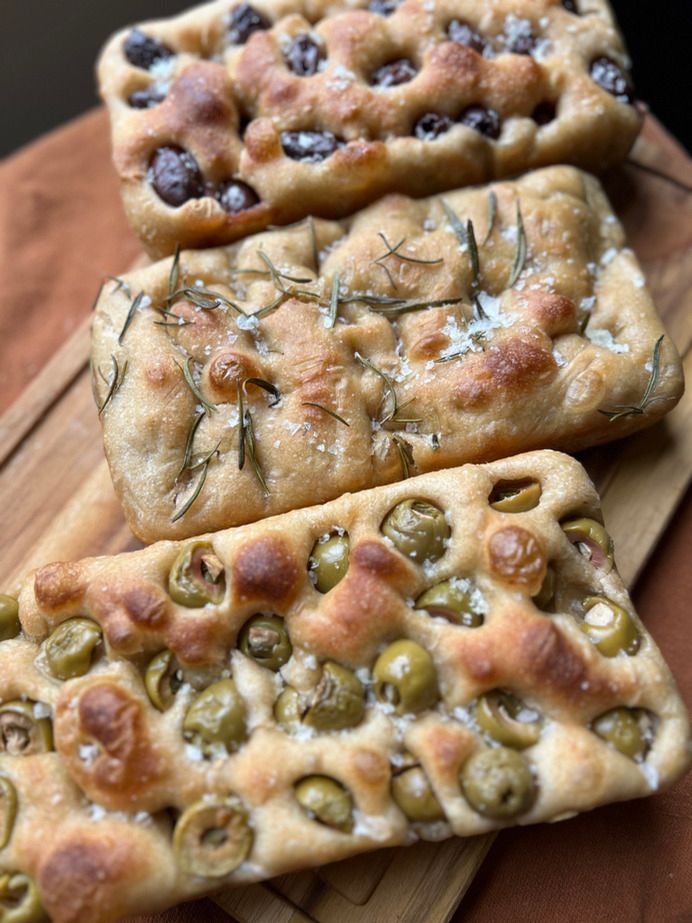 Three focaccias on a board: Kalamata, green olive with jalapeño, and rosemary.